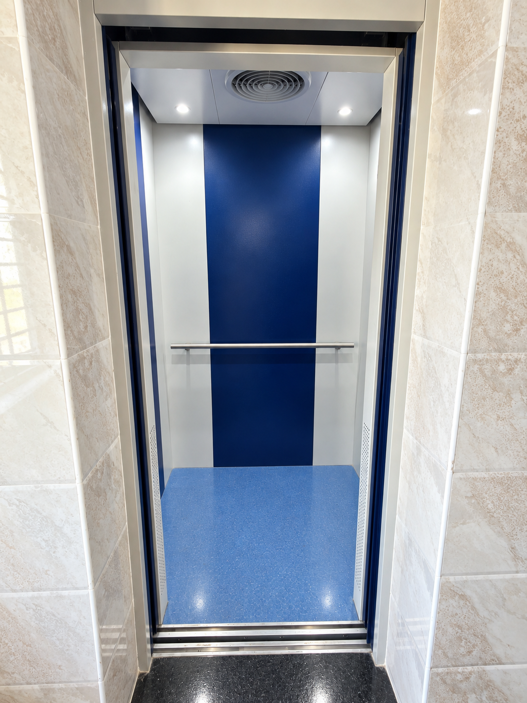 Fine Dine Academy lift cabin seen through open doors with handrail and blue floor