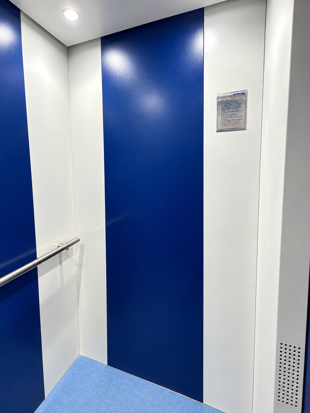 Interior of the Fine Dine Academy lift cabin with blue and white panels and handrail